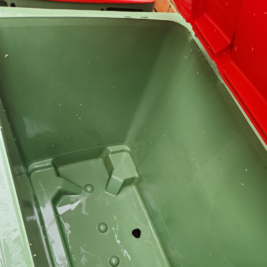 An empty green trash can with a lid, recently cleaned, displayed after strata maintenance in Sydney.