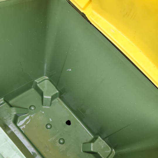 An empty green trash can with a lid, recently cleaned, displayed after strata maintenance in Sydney.