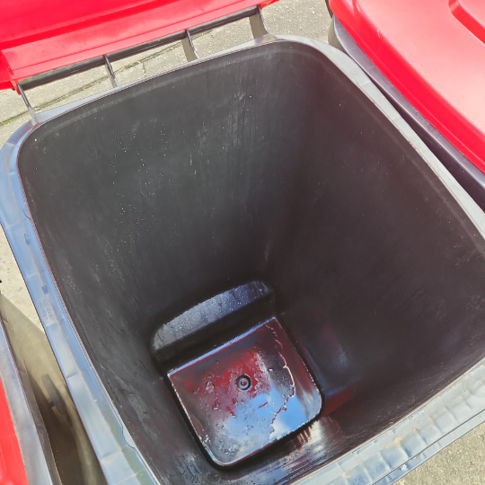 An empty black trash can with a lid, recently cleaned, displayed after strata maintenance in Sydney.