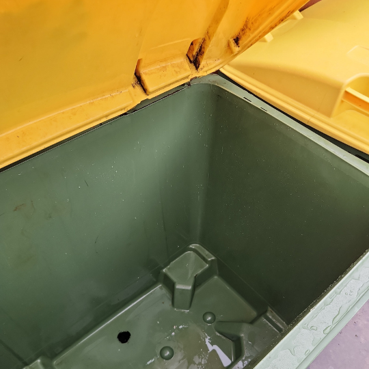 An empty green trash can with a lid, recently cleaned, displayed after strata maintenance in Sydney.