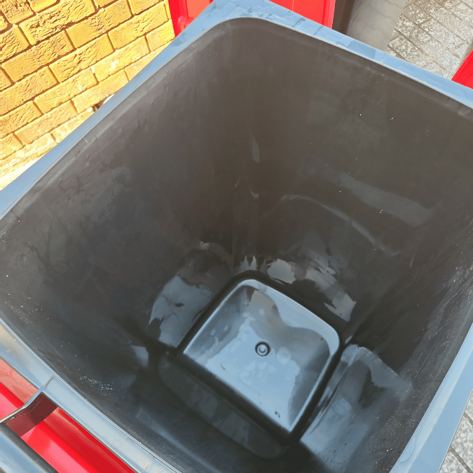 An empty black trash can with a lid, recently cleaned, displayed after strata maintenance in Sydney.