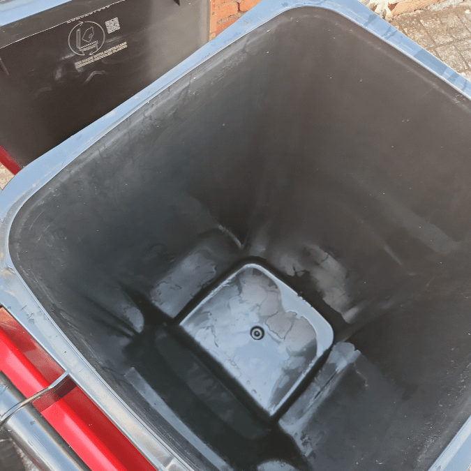 An empty black trash can with a lid, recently cleaned, displayed after strata maintenance in Sydney.